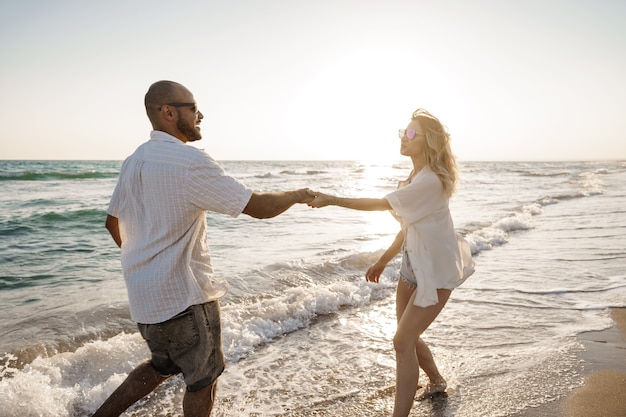 Hermosa joven pareja caminando en la playa cerca del mar