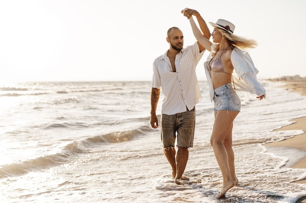 Hermosa joven pareja caminando en la playa cerca del mar