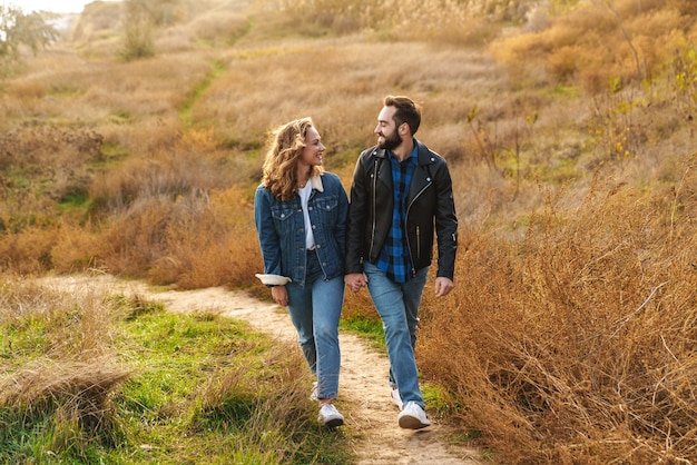 Hermosa joven pareja caucásica de citas y caminar juntos en el campo