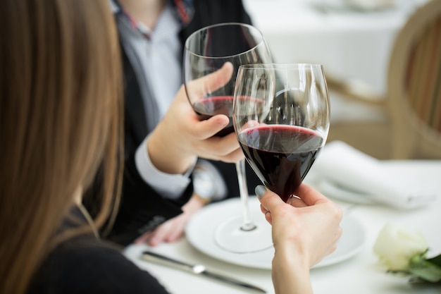 Hermosa joven pareja con copas de vino tinto en un restaurante de lujo