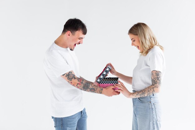 Hermosa joven pareja enamorada en casa celebrando con una caja de regalo y flores