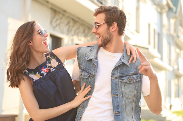 Hermosa joven pareja de enamorados caminando al aire libre en la calle de la ciudad, abrazándose.