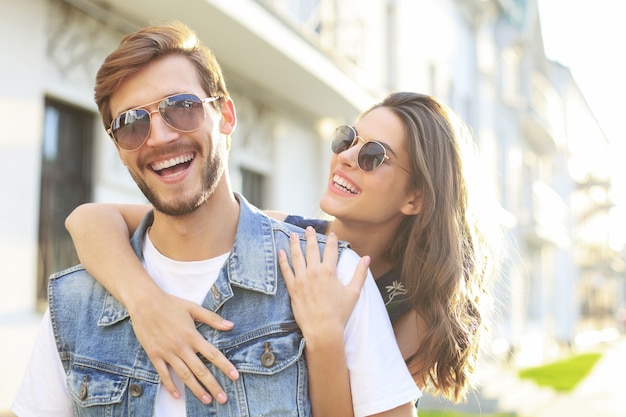 Hermosa joven pareja de enamorados caminando al aire libre en la calle de la ciudad, abrazándose.