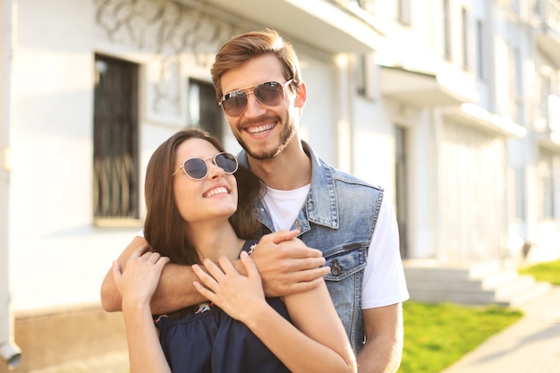 Hermosa joven pareja de enamorados caminando al aire libre en la calle de la ciudad, abrazándose.