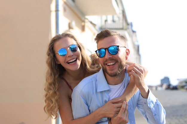 Hermosa joven pareja de enamorados caminando al aire libre en la calle de la ciudad, abrazándose.