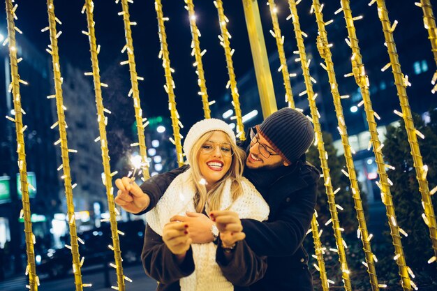 Hermosa joven pareja de enamorados disfrutando de la noche de Navidad o año nuevo en una calle de la ciudad.