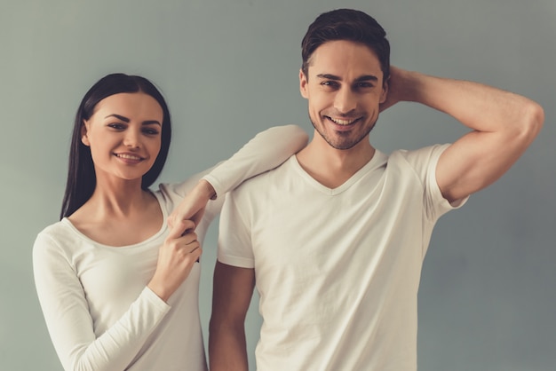 Hermosa joven pareja está mirando a cámara y sonriendo.