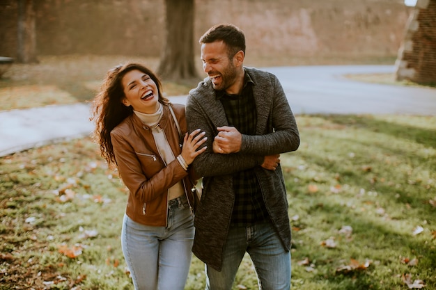 Hermosa joven pareja feliz caminando en el parque otoño