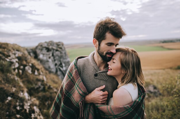 hermosa joven pareja en un fondo de acantilado de roca