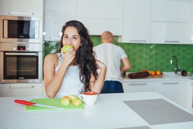 Hermosa joven pareja graficaba sonriendo mientras cocinaba en la cocina en casa.