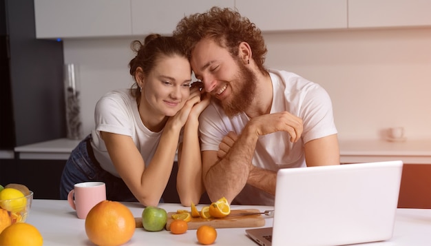 Hermosa joven pareja hablando por videollamada usando laptop.