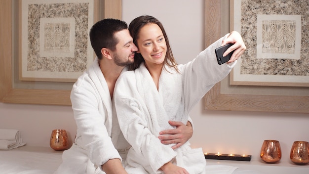 Hermosa joven pareja hace una selfie en el moderno salón de bienestar