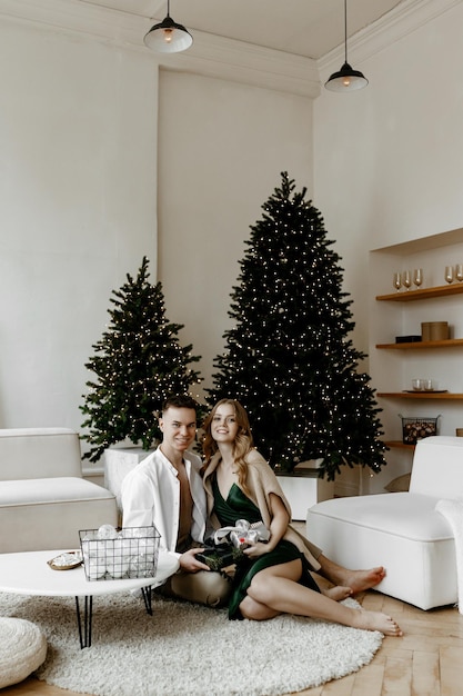 Hermosa joven pareja intercambiando regalos de Navidad en casa en una luminosa sala de estar