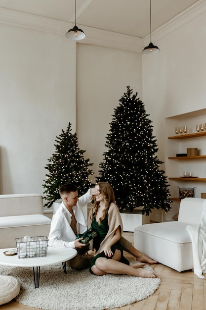 Hermosa joven pareja intercambiando regalos de Navidad en casa en una luminosa sala de estar