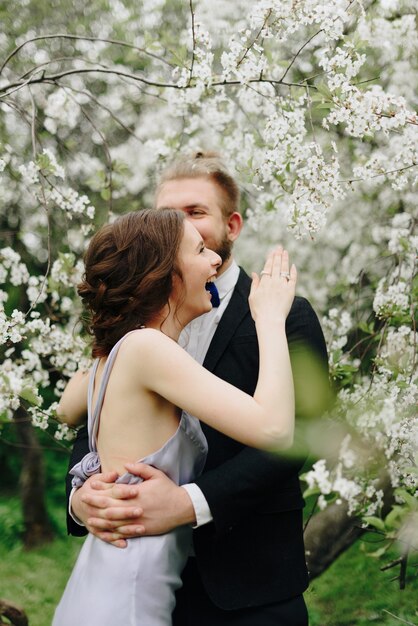 Foto hermosa joven pareja en el jardín con el telón de fondo de los cerezos en flor 1