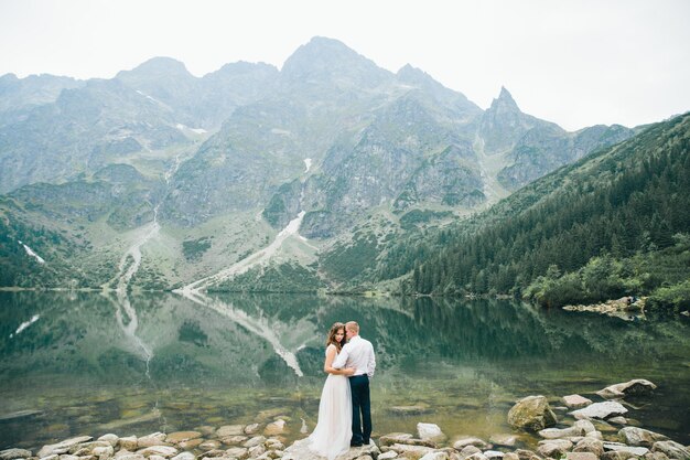 Una hermosa joven pareja en el lago en las montañas Tatra en Polonia Morskie Oko