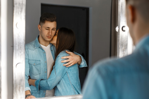 Hermosa joven pareja de moda cerca de un espejo vintage con luces