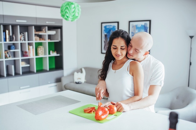 Hermosa joven pareja muele verduras juntos en la cocina.