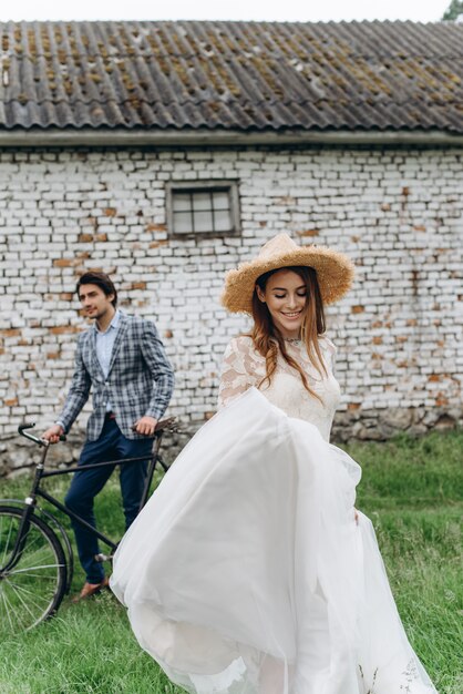 Una hermosa joven pareja novia y novio con una bicicleta cerca de casa antigua