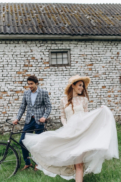 Una hermosa joven pareja novia y novio con una bicicleta cerca de casa antigua