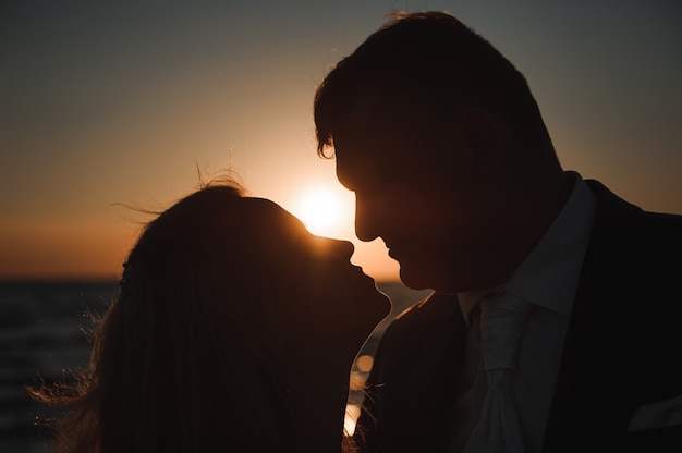 Hermosa joven pareja en la playa al atardecer.