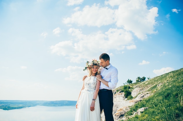 hermosa joven pareja posando en la roca cerca del lago
