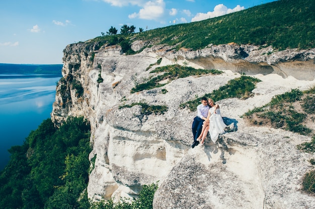 hermosa joven pareja posando en la roca cerca del lago