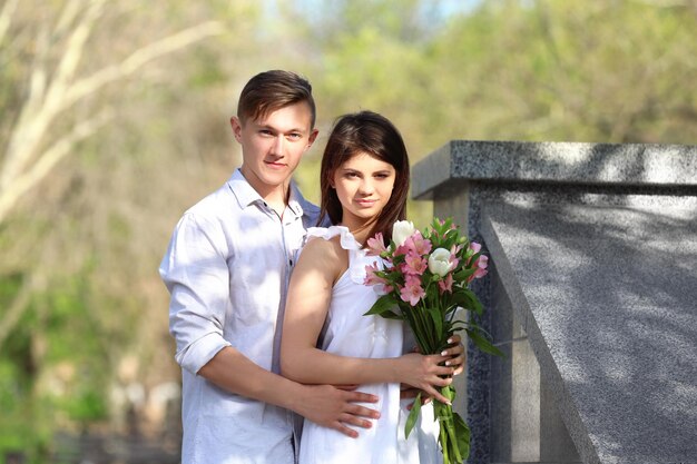 Hermosa joven pareja con ramo de flores al aire libre