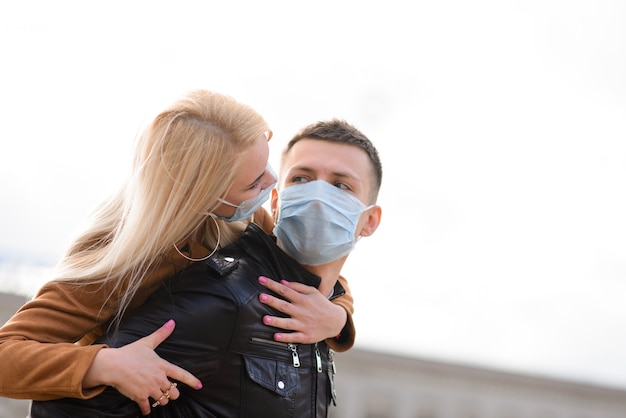 Hermosa joven pareja romántica disfrutando de tiempo juntos con máscaras protectoras