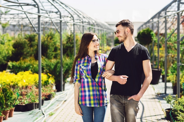 Hermosa joven pareja en ropa casual es elegir plantas y sonriendo