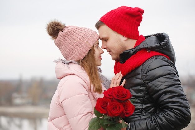 Hermosa joven pareja con rosas rojas al aire libre