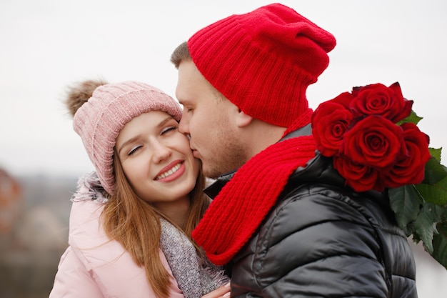 Hermosa joven pareja con rosas rojas al aire libre