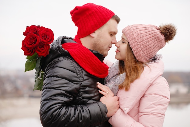 Hermosa joven pareja con rosas rojas al aire libre
