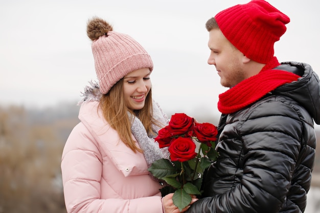 Hermosa joven pareja con rosas rojas al aire libre