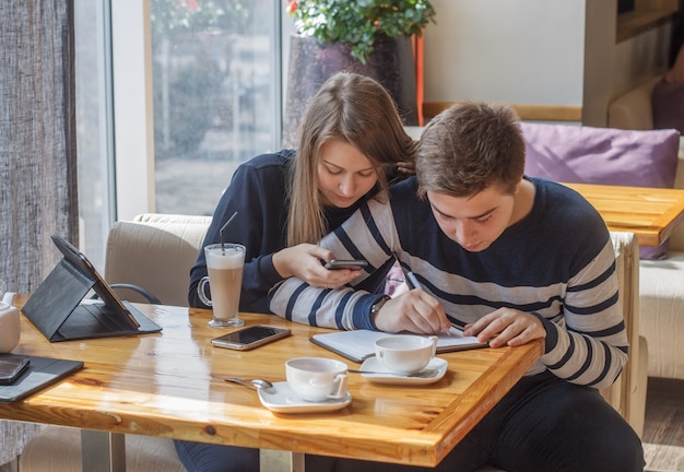 Hermosa joven pareja sentada en una acogedora cafetería Pareja de enamorados haciendo planificación de la vida