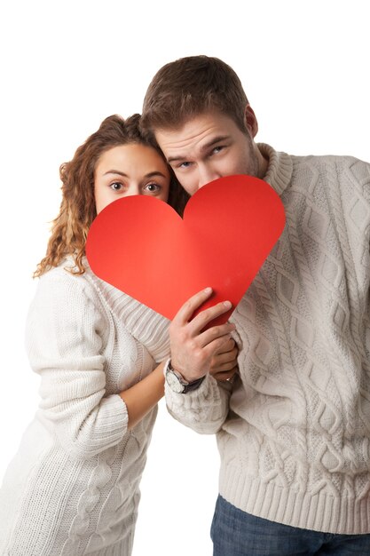 Hermosa joven pareja sosteniendo un corazón rojo aislado sobre fondo blanco.