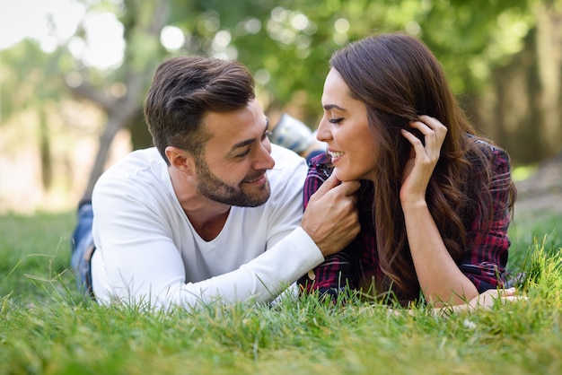 Hermosa joven pareja tirado en el césped en un parque urbano.