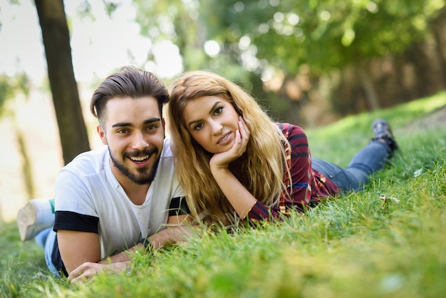 Hermosa joven pareja tirado en el césped en un parque urbano.