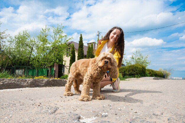 Hermosa joven paseando al perro en un día soleado.