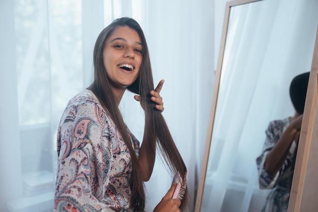 Hermosa joven peinándose frente a su espejo