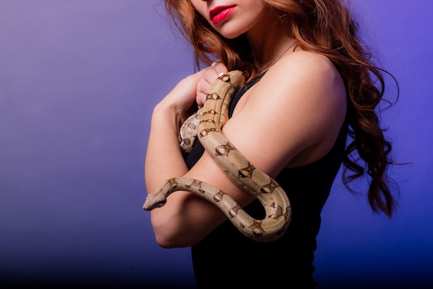 Hermosa joven pelirroja con serpiente con un maquillaje perfecto de moda