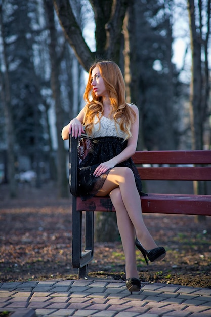 Hermosa joven pelirroja con un vestido en el parque. Hermosa joven con el pelo largo y rizado rojo