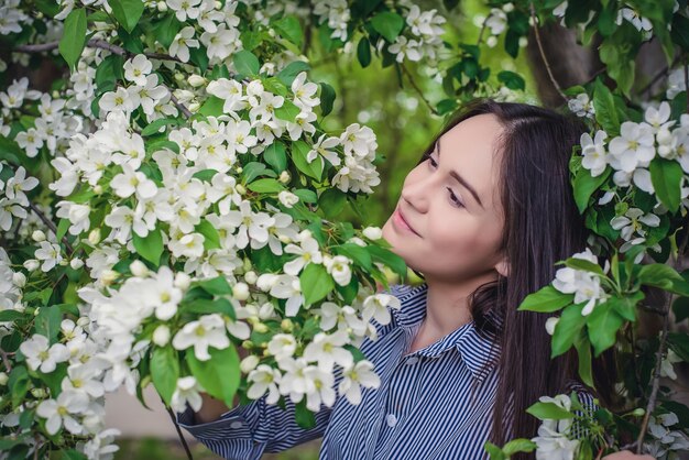 Hermosa joven de pelo largo cerca de manzanos florecientes en primavera