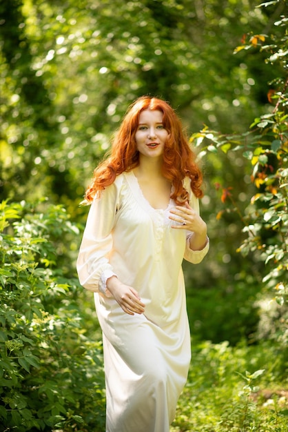 Hermosa joven con el pelo largo y rojo al aire libre en un estilo romántico