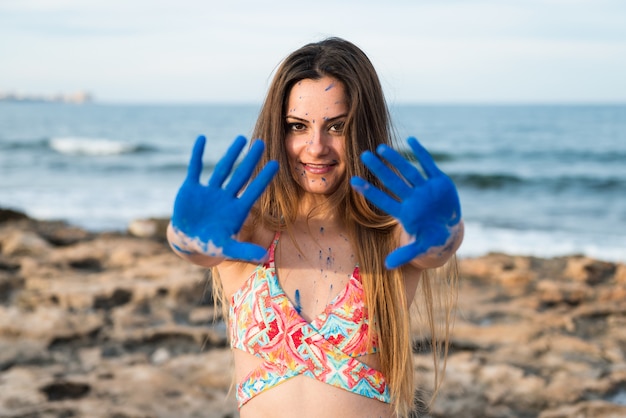 Hermosa joven en la playa con holi de color azul