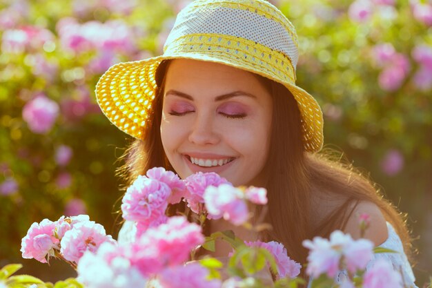 Hermosa joven posando cerca de rosas en un jardín