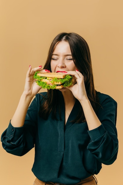 Hermosa joven posando con un sándwich en un fondo de color