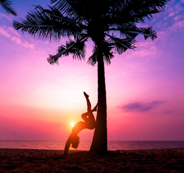 Hermosa joven practic yoga en la playa. Ejercicio temprano en la mañana. amanecer