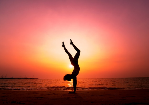 Hermosa joven practic yoga en la playa. Ejercicio temprano en la mañana. amanecer