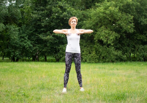 Hermosa joven practica deportes en el parque en la naturaleza. La mujer se dedica a la aptitud en ropa deportiva.